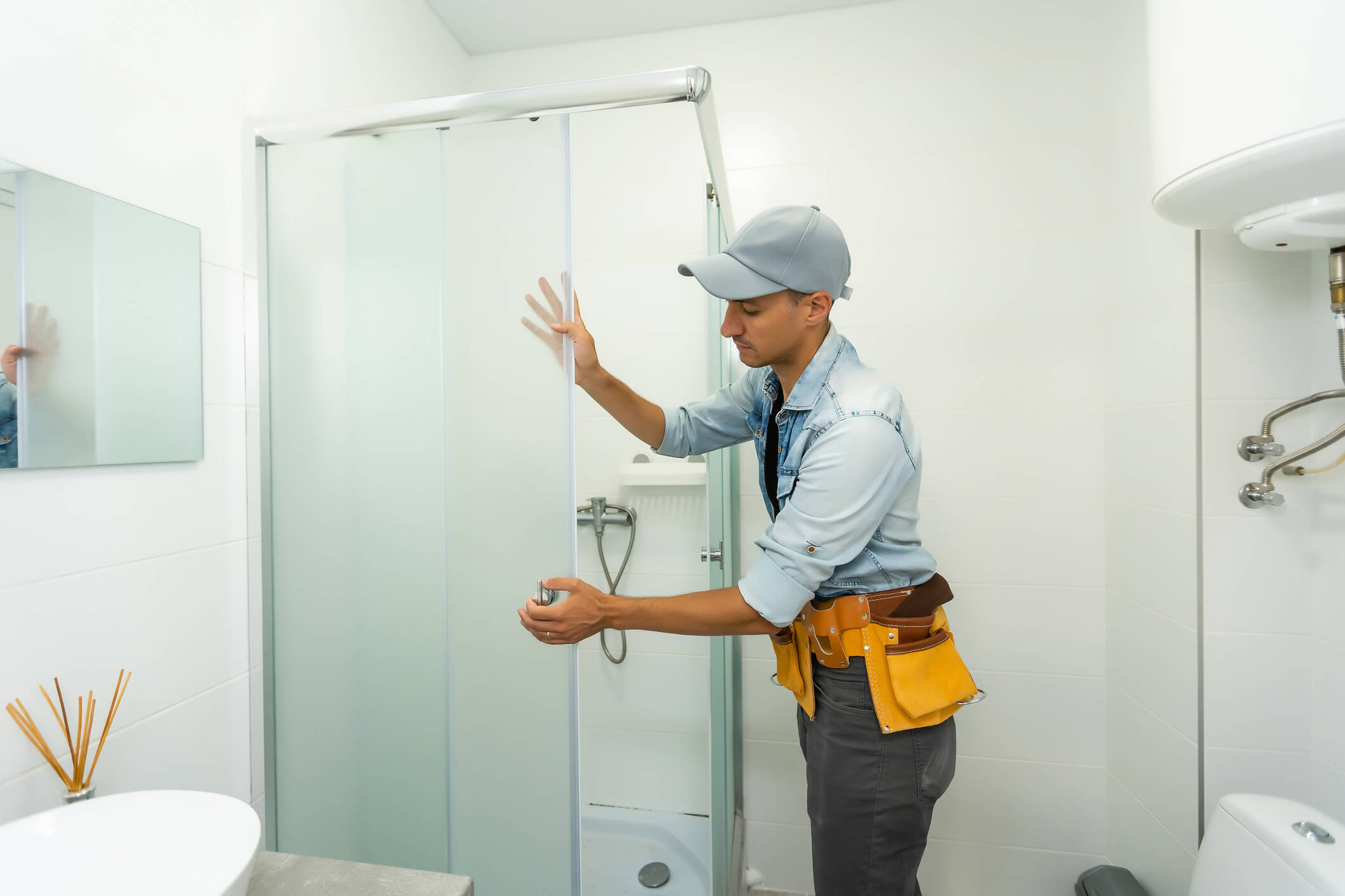 Un poseur qui pose la vitre du douche dans une salle de bain